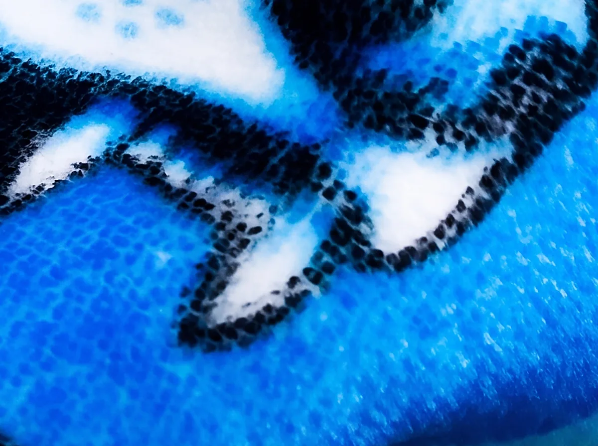 Close macro of a printed fang and dark linework, each fiber carrying the design